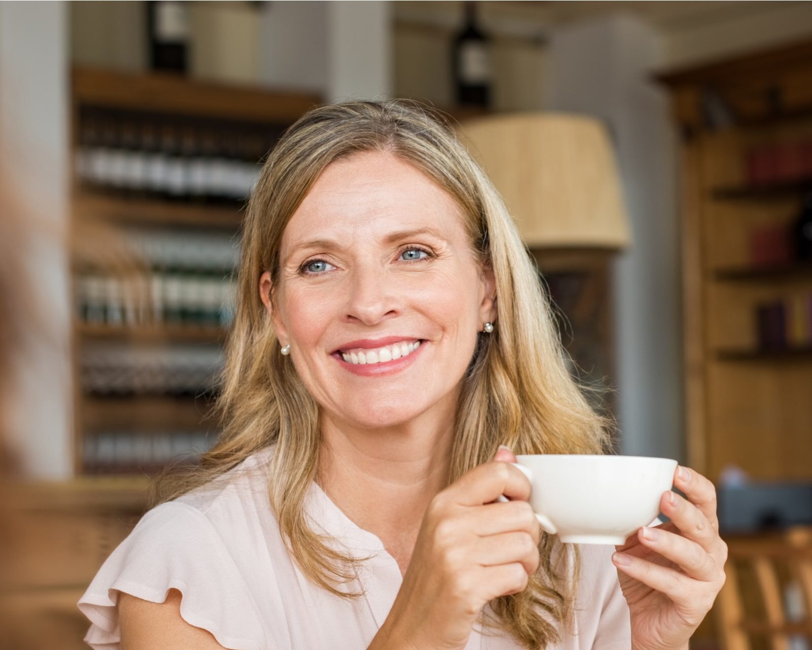 Mature woman holding coffee cup and talking with her friend