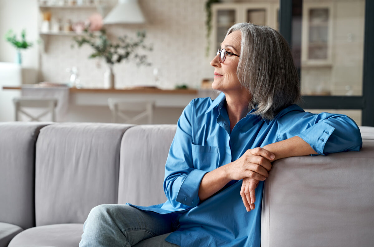 Calm relaxed mature older woman relaxing sitting on couch at home