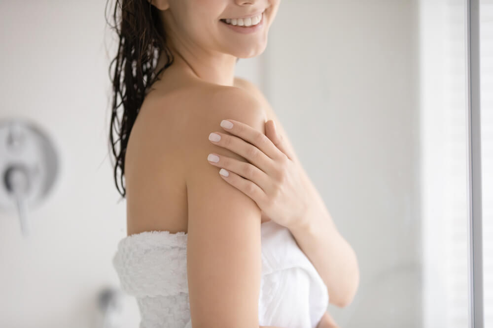 Close up of smiling young woman touch soft healthy glowing skin
