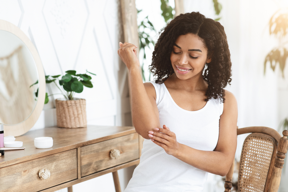 Smiling Black Woman Applying Moisturising Cream At Home, Healing Cracked Skin