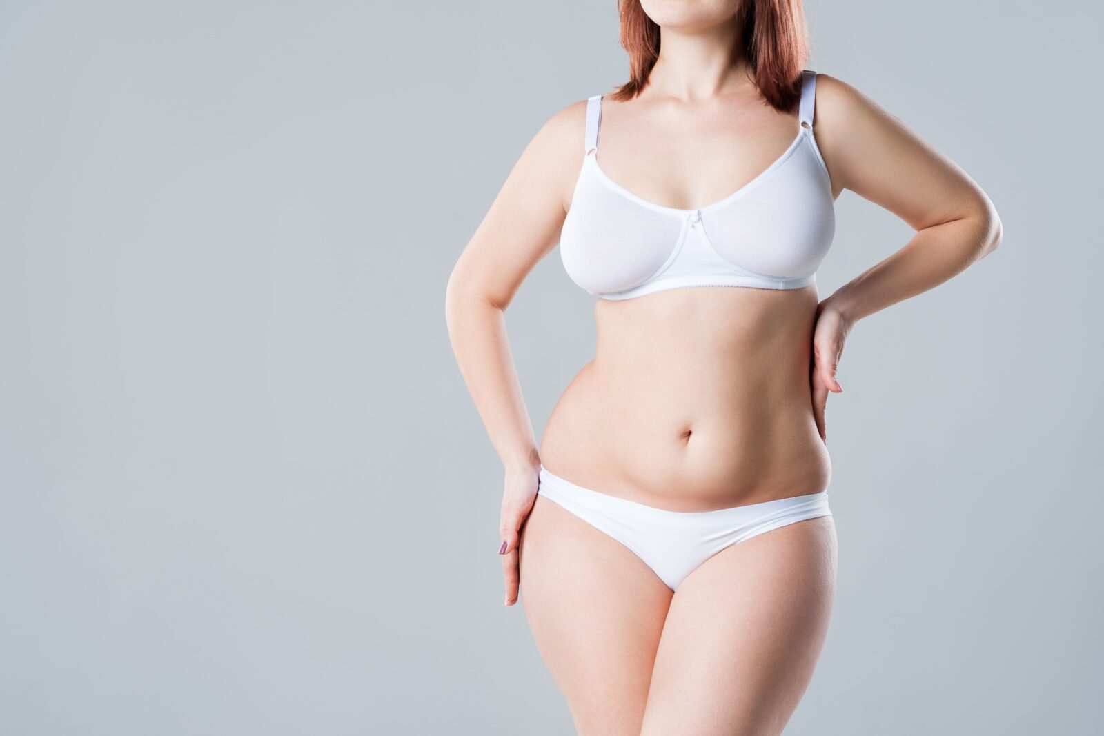 woman standing in white after receiving a lower body lift