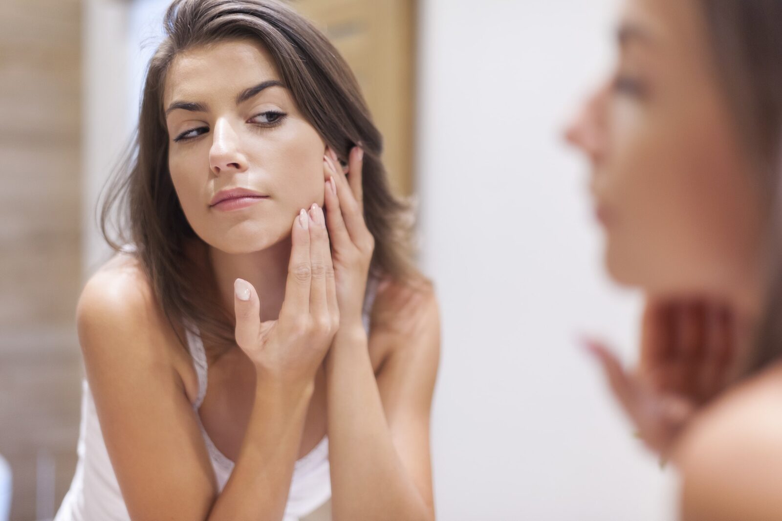 A woman looking at her cheeks deciding if she would benefit from a midface lift