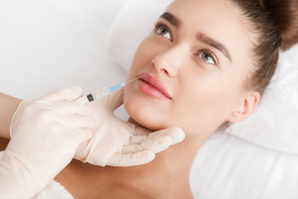 Lip augmentation. Young woman receiving hyaluronic acid injection in salon