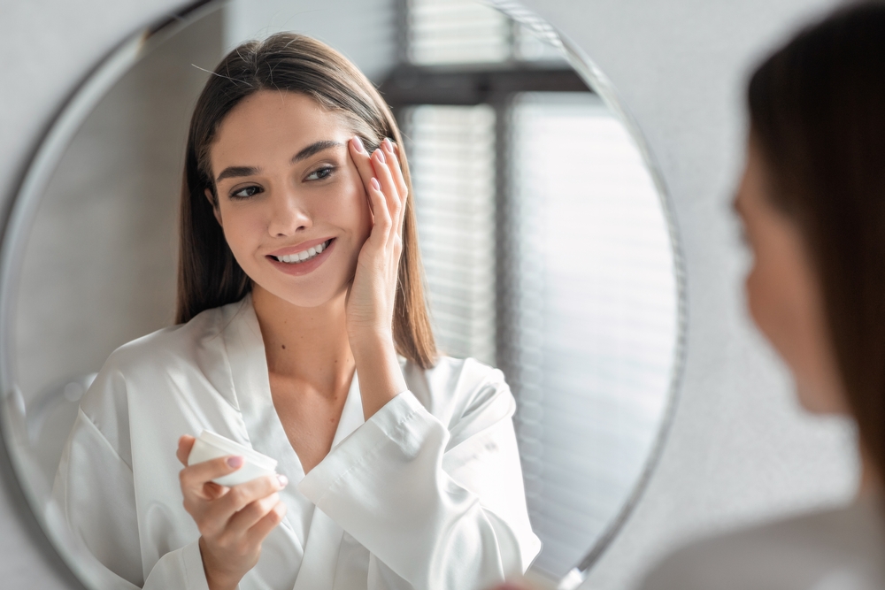 A woman smiling in the mirror happy with the results of her Hormone Test Panel for Women