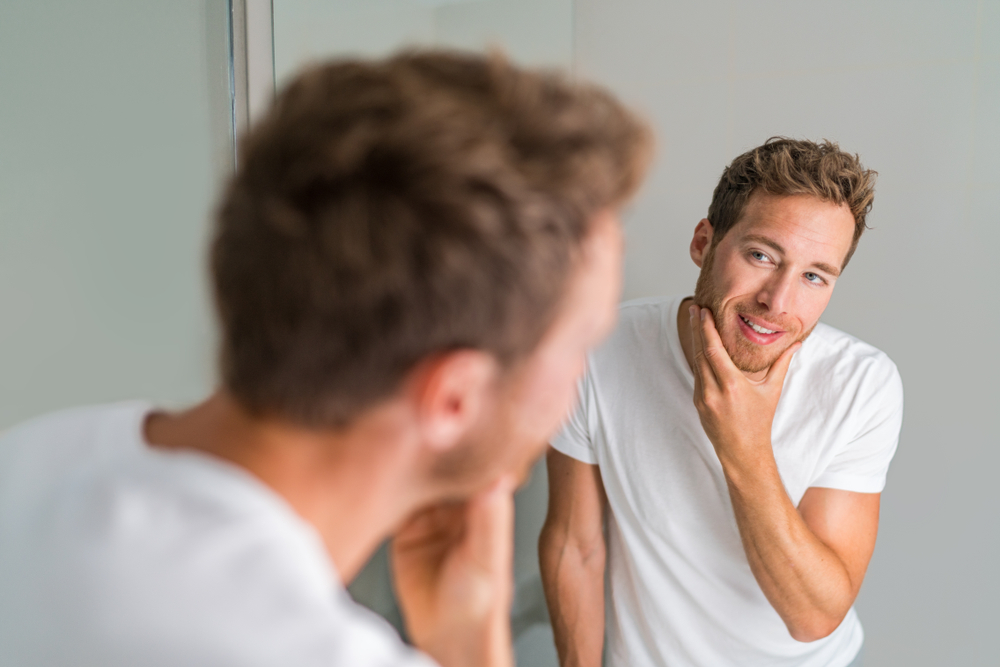 Man looking into the mirror happy after receiving the results of his Hormone Test Panel for Men