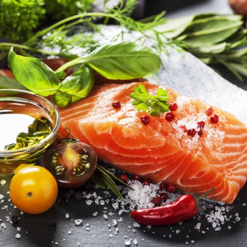Delicious portion of fresh salmon fillet with aromatic herbs, spices and vegetables - healthy food, diet or cooking concept