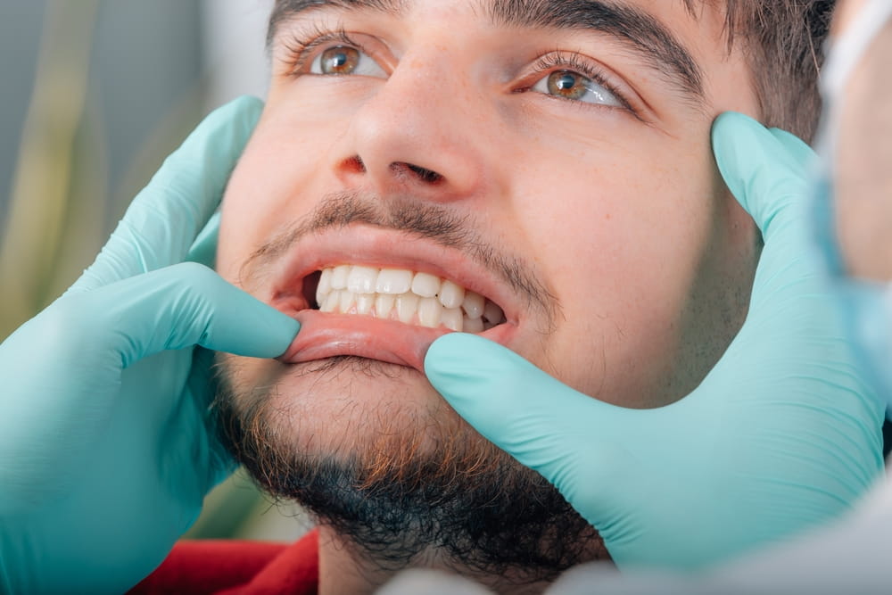 hands of dentist checking denture of patient in clinic