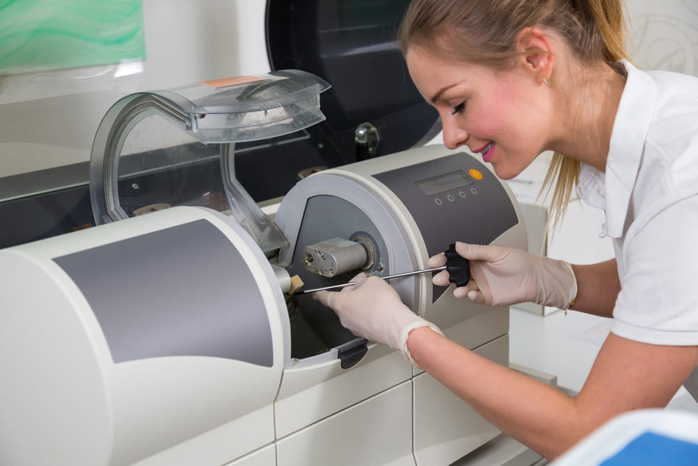 Dentist's assisstant operating CEREC Milling machine to produce dental implants