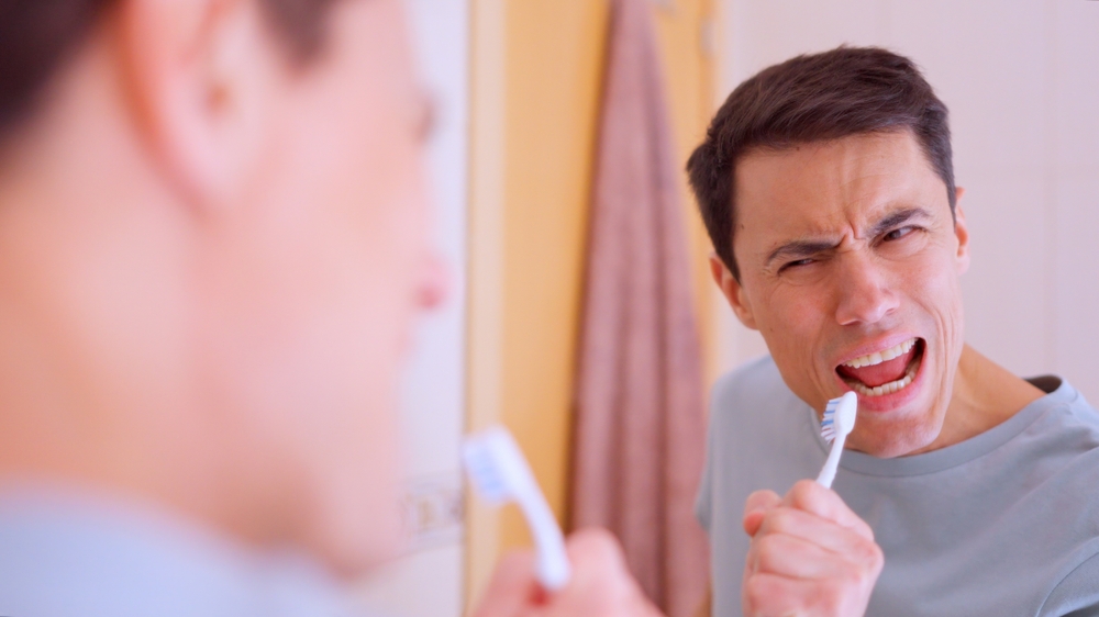 Man singing with toothbrush in bathroom mirror reflection
