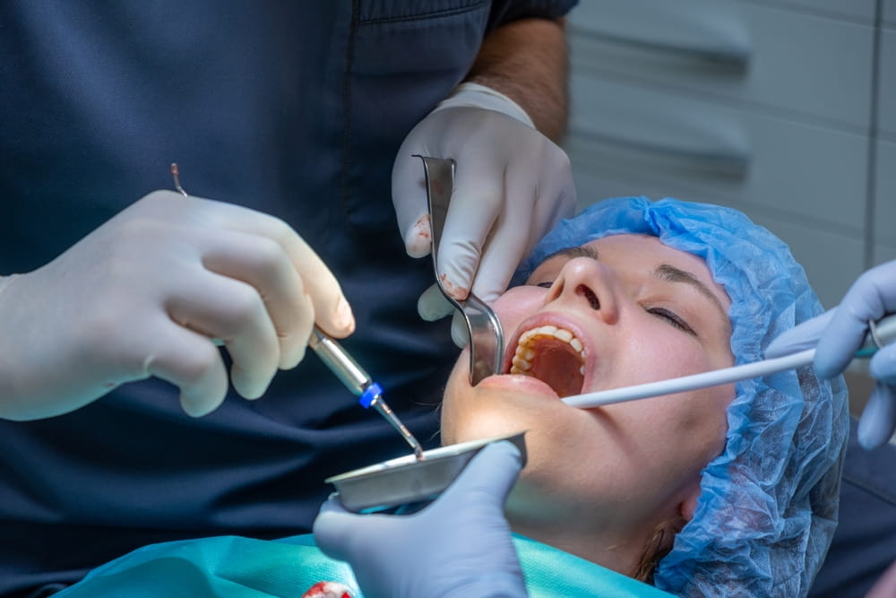 Dental professional works on patient mouth during application of bone graft material.