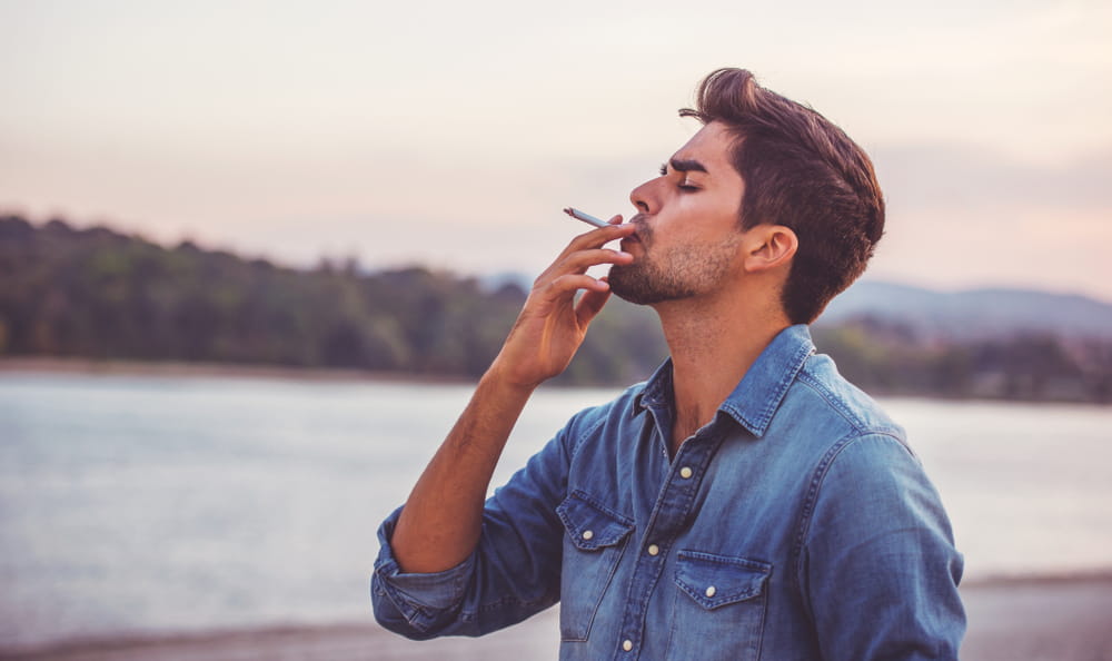 Handsome young man smoking cigarette