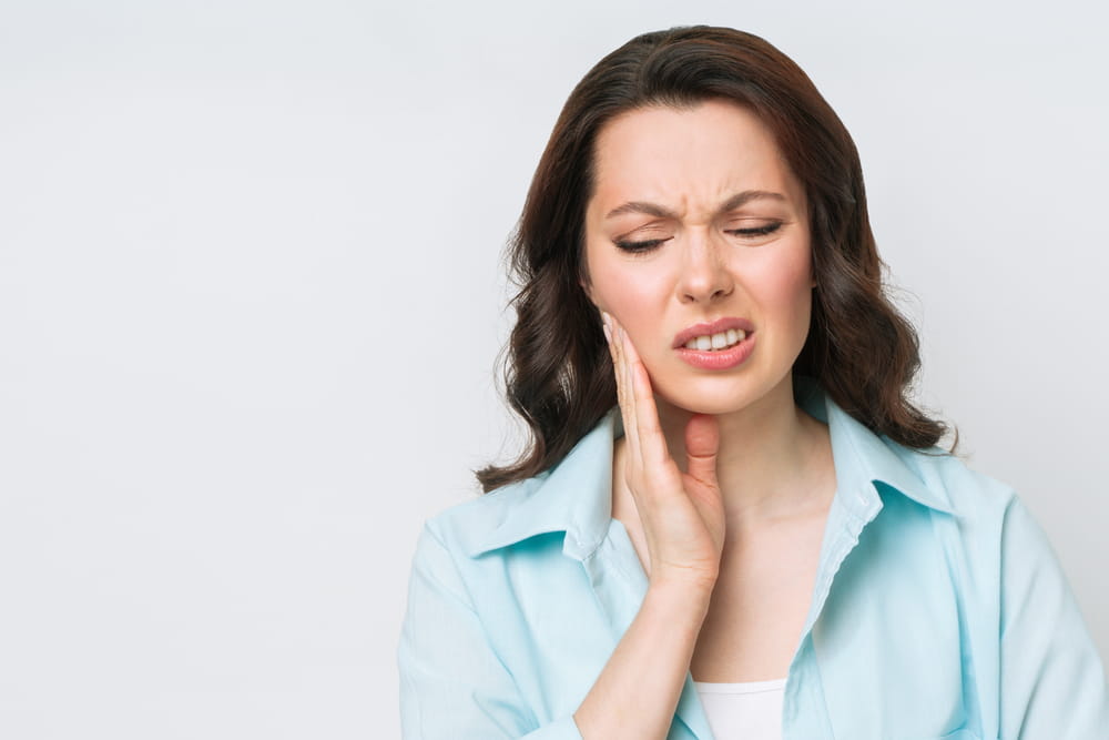 Young Woman Suffering From Strong Teeth Pain, Touching Cheek With Hand. Dentistry Concept