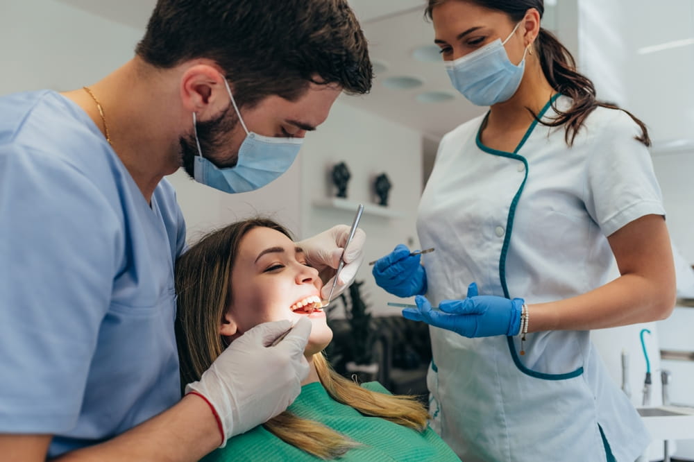Attractive young woman in stomatology clinic being examined by a male dentist.