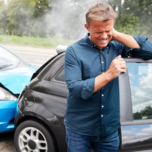 Mature Male Motorist With Whiplash Injury In Car Crash Getting Out Of Vehicle