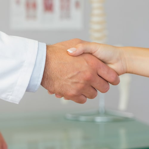 Close up of patient shaking hands with doctor in bright office