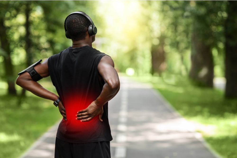 Back view of black sportsman touching sore zone on his back