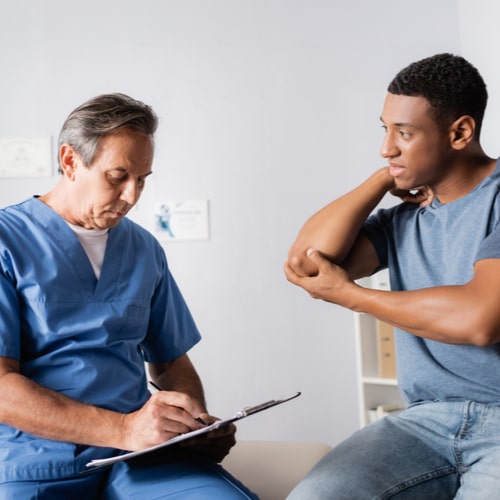 mature doctor writing prescription near injured african american man