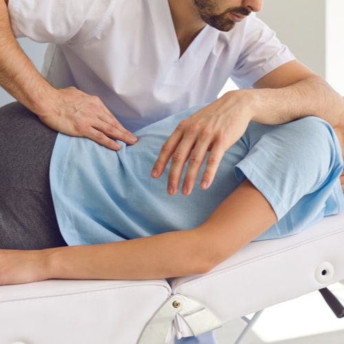 Professional chiropractor or physiotherapist helps to heal a young woman's back