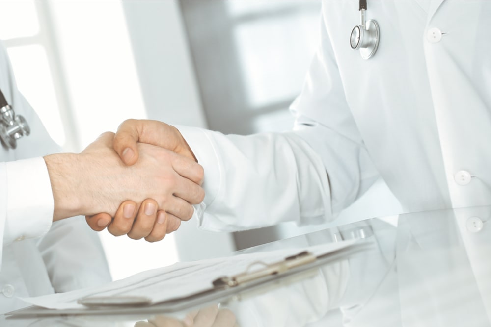 Two doctors are shaking hands as agreement about patient's treatment, close-up