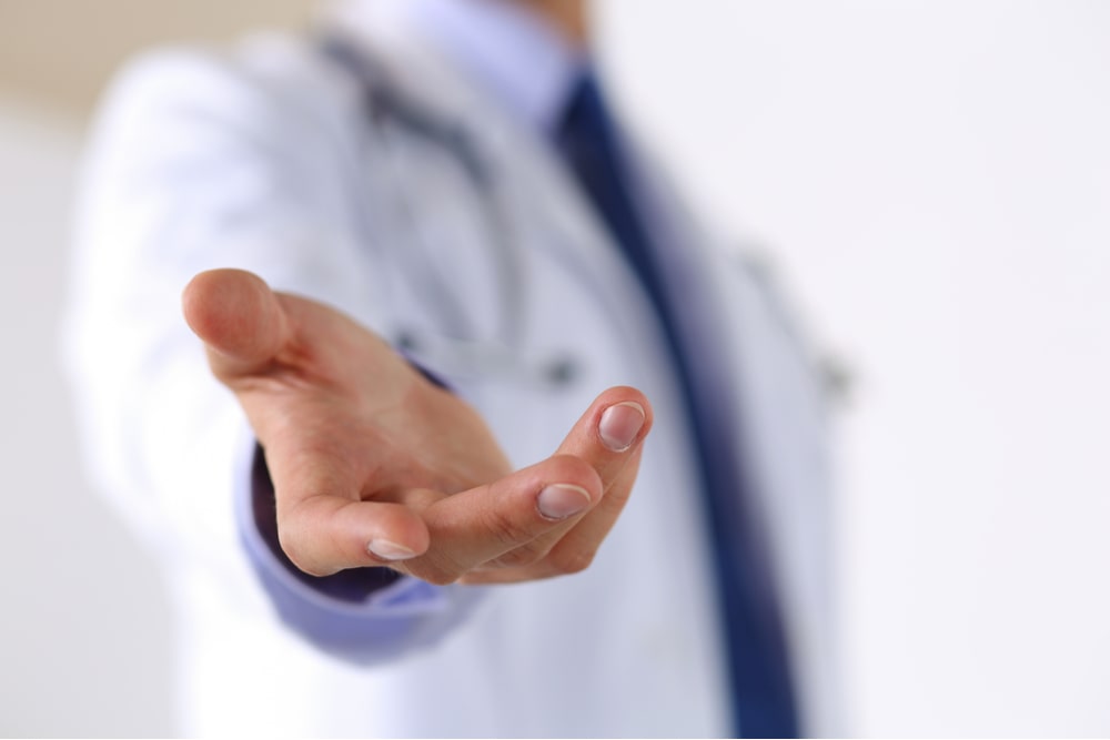 Male medicine doctor offering helping hand in office closeup. Friendly and cheerful gesture