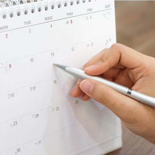 close up on woman hand with pen writing on calender 2026 for note or make appointment concept.