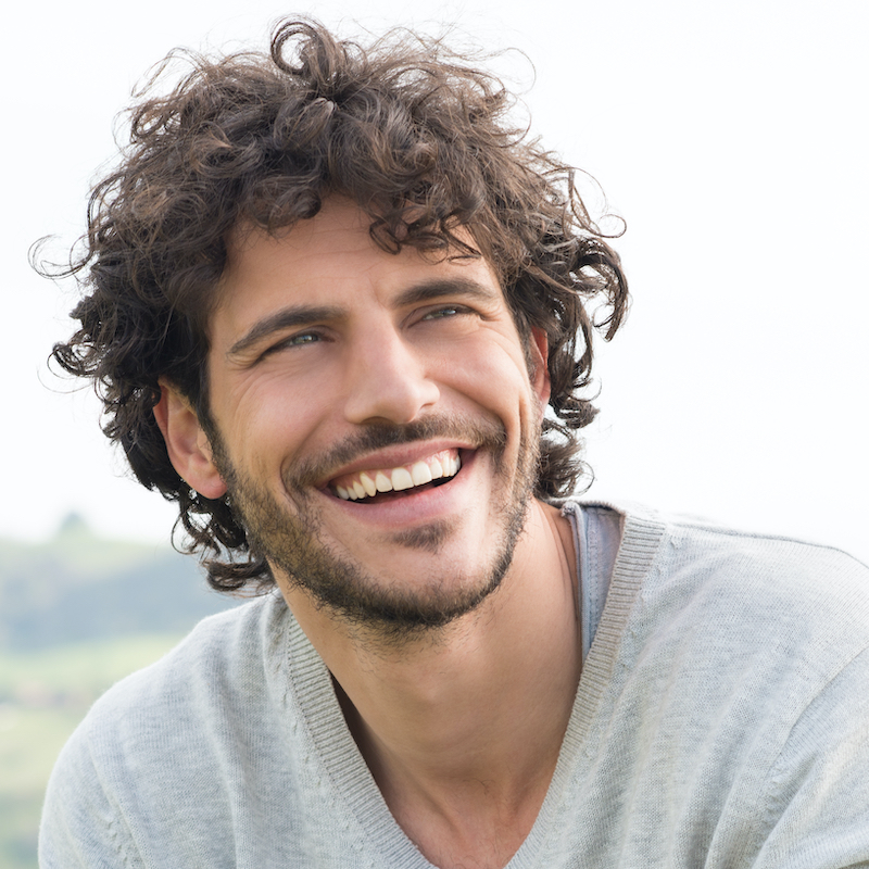 Man with curly hair smiling away from the camera
