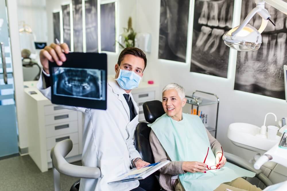 older dental patient review dental x-rays with dentist